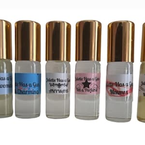 May include: Six small glass bottles with gold lids and labels that say "Juliette Has a Gun" with different scents. The scents are "Gentlewoman", "Charming", "Anyways", "Not a Perfume", "Mum", and "Mad Madam".