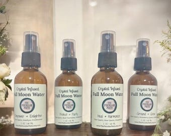 May include: Four amber glass bottles with spray tops, each labeled "Crystal Infused Full Moon Water" with a different crystal and affirmation. The bottles are arranged on a wooden shelf.