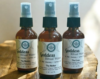 May include: Three brown glass bottles with black spray tops and white labels. The labels have a crescent moon design and the text "Goddess Ritual Water" with the names "The Maiden", "The Mother", and "The Crone" below. Each bottle contains 2 ounces (60 ml) of liquid.