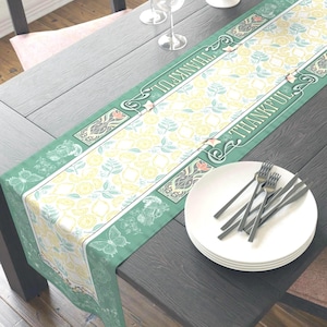 May include: A rectangular table runner with a floral pattern in yellow and white, framed by a green border. The words "THANKFUL" are printed on the border. The table is set with plates, forks, wine glasses, and a bowl of apples.