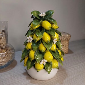 May include: A ceramic lemon tree figurine with yellow lemons and green leaves. The tree is in a white pot.