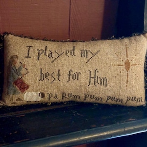 May include: A beige pillow with brown fringe and embroidered text that reads "I played my best for Him" with a small star design and a sheep at the bottom.