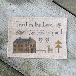 Peut inclure: Point de croix sur tissu beige avec le texte "Trust in the Lord for HE is good." Comprend une maison, un oiseau, un arbre et une clôture dans des tons de marron, vert et bleu. Le sampler est rectangulaire.