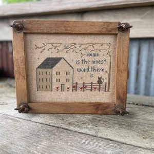 May include: A framed cross-stitch featuring a house, a cat, and the text "Home is the nicest word there is."