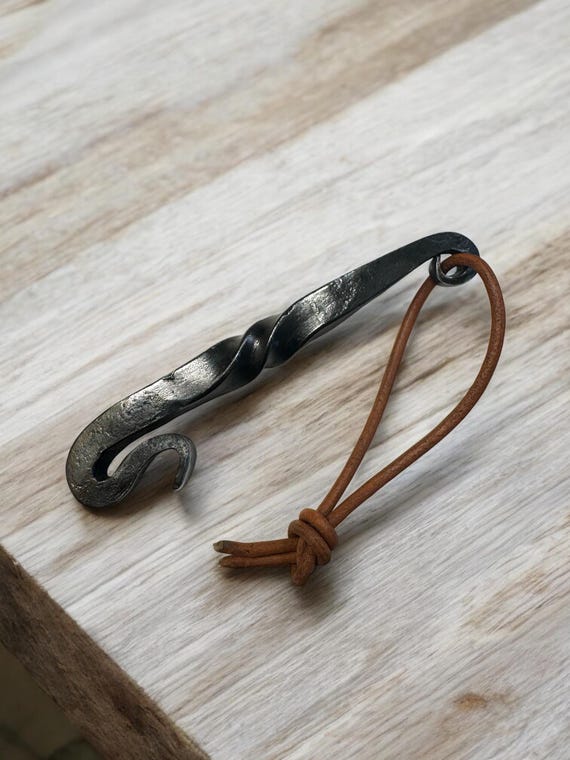 Hand-forged twisted steel handle with a leather lanyard — this looks like it came from a blacksmith's workshop, not a factory, and it did.