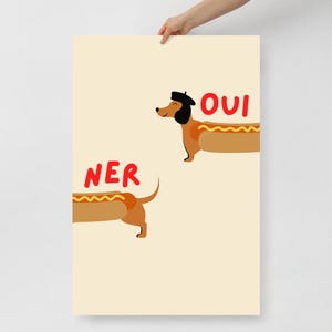 K&ouml;nnte beinhalten: Ein Poster mit hellbeigem Hintergrund zeigt zwei Cartoon-Dackel in Form von Hotdogs. Einer tr&auml;gt ein Barett und das Wort "OUI" steht rot dar&uuml;ber. Das Wort "NER" steht &uuml;ber dem anderen Dackel.