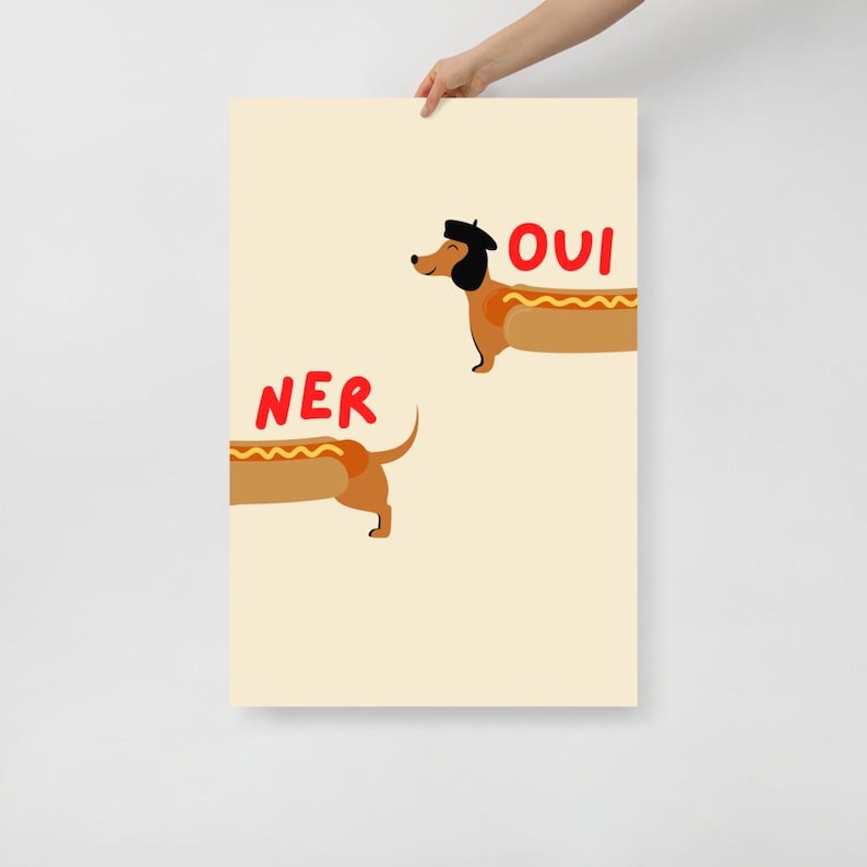 K&ouml;nnte beinhalten: Ein Poster mit hellbeigem Hintergrund zeigt zwei Cartoon-Dackel in Form von Hotdogs. Einer tr&auml;gt ein Barett und das Wort "OUI" steht rot dar&uuml;ber. Das Wort "NER" steht &uuml;ber dem anderen Dackel.
