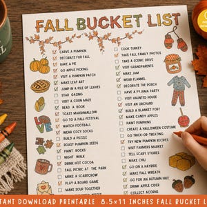 May include: A printed Fall Bucket List checklist on white paper featuring colorful illustrations of seasonal items like pumpkins, pies, and cozy clothing. The list includes various autumn activities with checkboxes, some marked with red checkmarks.