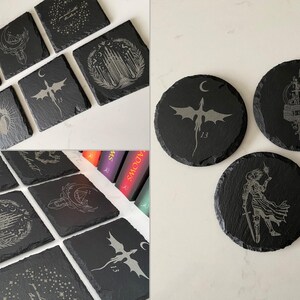 K&ouml;nnte beinhalten: Set mit 10 schwarzen Schieferuntersetzern mit verschiedenen gravierten Designs, darunter Drachen, Burgen und Sterne. Die Untersetzer haben einen Durchmesser von etwa 10 cm.