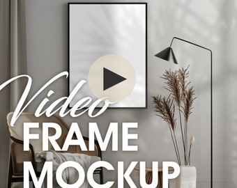 May include: A black video frame mockup in a modern living room setting. The frame is on a white wall with a beige rug, a wooden side table, a wicker chair, a potted plant, and a black floor lamp.