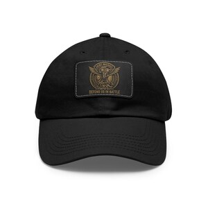 May include: Black baseball cap featuring a rectangular patch with the words "SAINT MICHAEL" above an illustration of an angel with outstretched wings. The text "DEFEND US IN BATTLE" is below the illustration. The cap has a curved brim.