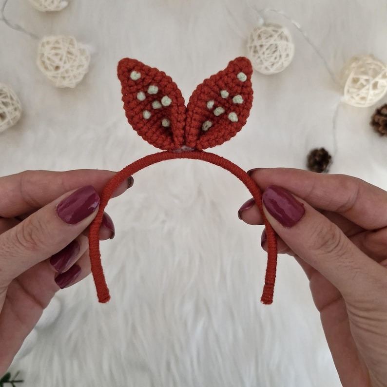 Op de afbeelding: Een rood hoofdband met witte stippen en gehaakte konijnenoren.