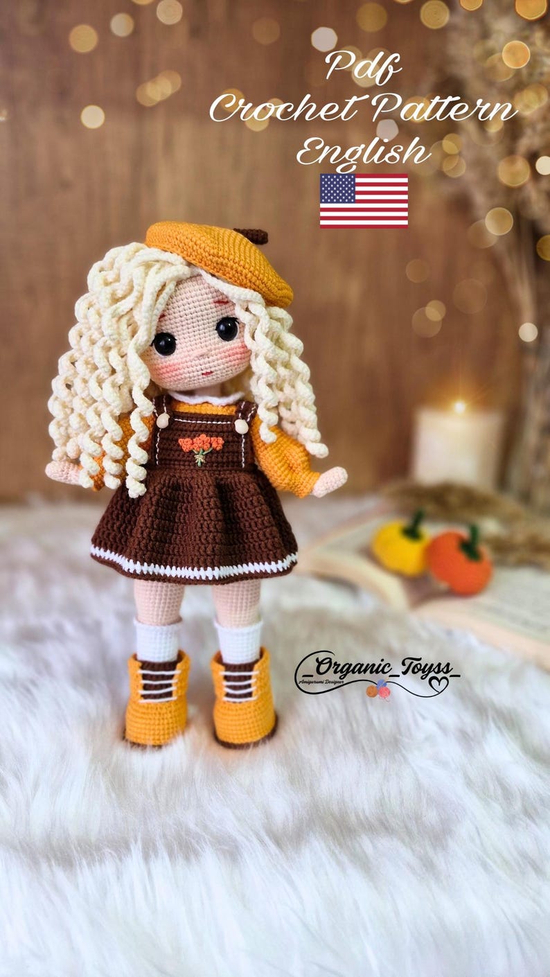 Pode incluir: Padr&atilde;o de boneca de croch&ecirc; em ingl&ecirc;s. A boneca est&aacute; vestindo um vestido marrom com uma borda branca, um su&eacute;ter amarelo, um bon&eacute; amarelo e sapatos amarelos. A boneca tem cabelo loiro encaracolado e olhos castanhos. O fundo &eacute; uma superf&iacute;cie de madeira com um livro e uma vela.