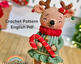 May include: A crocheted reindeer doll with a red scarf, green dress, and a candy cane. The doll has brown antlers, a gold bell, and the text "Crochet Pattern English Pdf". The doll is part of the "ToysDokloop" collection.