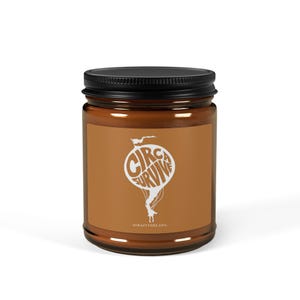 Puede incluir: Un tarro de vela de vidrio marrón con una tapa negra. La etiqueta es naranja con texto blanco que dice "Circa Survive" en un diseño circular. El texto "Draft Dreads" está impreso en blanco en la parte inferior de la etiqueta.