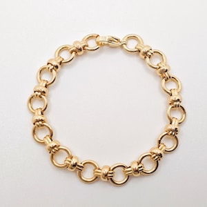 May include: Gold-coloured bracelet with a series of interconnected circular links. The bracelet has a polished finish and a secure clasp. This jewellery piece is suitable for various occasions.