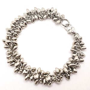 May include: Silver bracelet with a series of clustered, teardrop-shaped links. The bracelet has a lobster clasp closure. The design gives the bracelet a textured, organic appearance, suitable for everyday wear or special occasions.