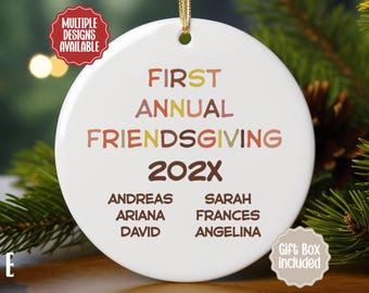 Puede incluir: Un adorno redondo de cerámica blanca con un cordón dorado para colgar. El texto dice FIRST ANNUAL FRIENDSGIVING 202X, seguido de los nombres ANDREAS, ARIANA, DAVID, SARAH, FRANCES y ANGELINA en letras marrones, naranjas y amarillas.