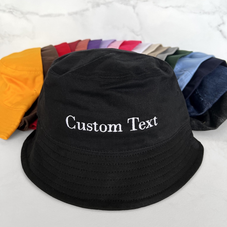 May include: A black bucket hat with the text "Custom Text" embroidered in white on the front.