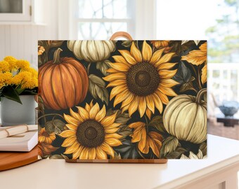 May include: Rectangular cutting board featuring a vibrant autumn design. The artwork showcases orange pumpkins, creamy white gourds, and large yellow sunflowers with dark brown centers, set against a dark background. The board has a wooden handle.