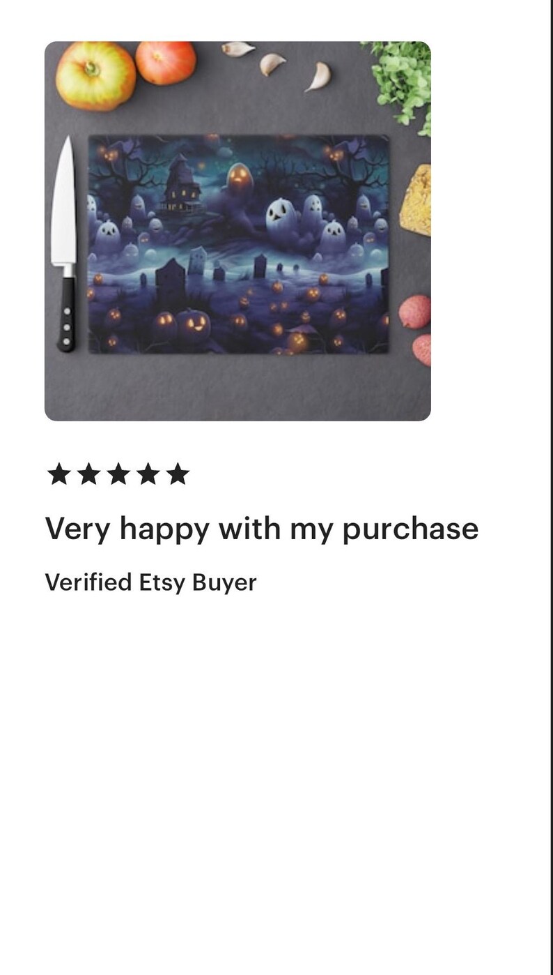 May include: A rectangular glass cutting board with a spooky Halloween design. The artwork features a haunted house, ghosts, and jack-o'-lanterns in a dark, eerie landscape. A chef's knife and some produce are next to the board.