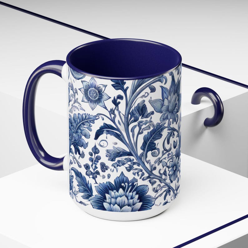 May include: A white ceramic mug with a blue floral pattern and a dark blue interior and handle. The floral design features detailed blue flowers and foliage against a white background. The mug is a standard size for hot beverages.