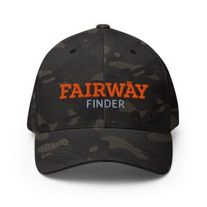 Può includere: Un cappellino da baseball mimetico nero e verde con le parole "FAIRWAY FINDER" ricamate in arancione e bianco. Il cappellino ha una visiera curva e una vestibilità strutturata.