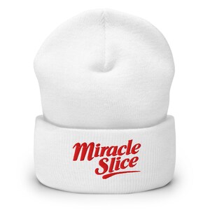 May include: A white beanie hat with the red text "Miracle Slice" in a cursive font. The hat is made of a soft, knitted material and has a folded brim. A winter accessory.