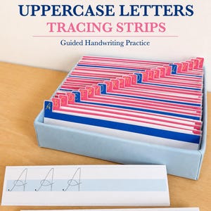 May include: A set of uppercase letters tracing strips in a light blue box. The strips feature pink tabs with gold letters A through Z. Two white strips with light blue centre lines show dotted cursive A and B letters for handwriting practice.