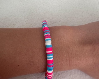May include: A colorful bracelet made of pink, blue, and white beads. The bracelet is made of round beads that are stacked on top of each other.