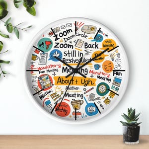 May include: White round wall clock with black hands and a white face. The clock face features colourful text and illustrations related to meetings, including "Zoom," "Meeting," and "Mandatory Fun Meeting."