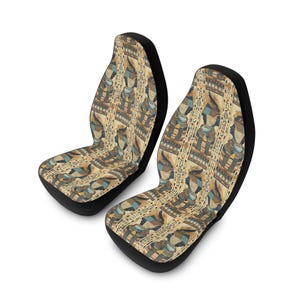 Może przedstawiać: Dwa pokrowce na siedzenia samochodowe z czarną podstawą i wzorem w stylu egipskim. Wzór przedstawia hieroglify i postacie w odcieniach beżu, niebieskiego i brązu. Siedzenia są przeznaczone do większości modeli samochodów.