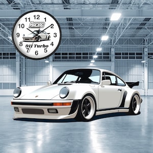 May include: A white Porsche 911 Turbo sports car with black accents and black wheels. The car is parked in a large, industrial-style garage with a clock on the wall that reads "Racing 911 Turbo".