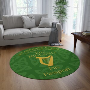 May include: A circular green rug featuring gold text and a gold harp emblem. The rug displays the word "Ireland" and "Pas Passport" in gold. The rug is placed on a wooden floor, in front of a white sofa.