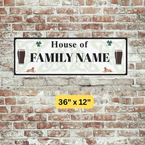 Peut inclure: Panneau rectangulaire en m&eacute;tal avec le texte "House of FAMILY NAME" en noir. Le panneau pr&eacute;sente deux verres &agrave; bi&egrave;re fonc&eacute;e, deux illustrations de chiens et des tr&egrave;fles. Le panneau mesure 91 cm x 30 cm.