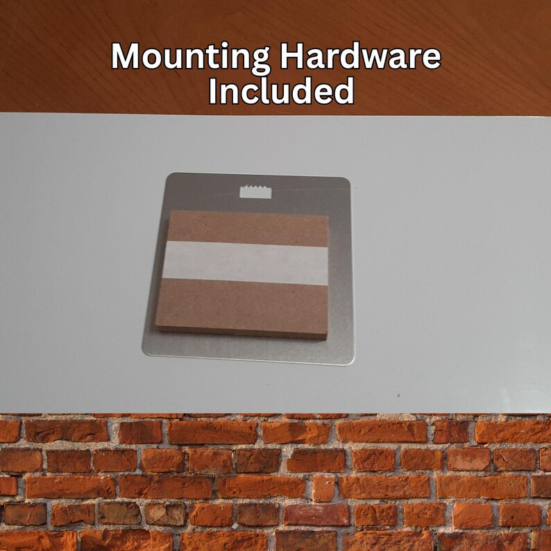 Peut inclure: Un support de montage en m&eacute;tal avec un dos en carton et du ruban adh&eacute;sif. Le texte "Mounting Hardware Included" est imprim&eacute; en haut. Le support est con&ccedil;u pour le montage mural.