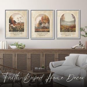 May include: Three framed landscape art prints with inspirational quotes. Each print features a serene outdoor scene with trees and fields, framed by an arch. The prints are displayed above a wooden cabinet in a living room setting. The text "Faith-Based Home Decor" is at the bottom.