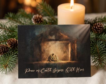 May include: A rectangular greeting card featuring a dark, painterly illustration of a nativity scene inside a stable. The text "Peace on Earth Begins With Him" is printed in a light, elegant script font at the bottom of the card's front surface.