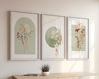 Könnte beinhalten: Drei gerahmte Drucke mit grünem Hintergrund und weißen Blumen. Die Drucke zeigen verschiedene Formen, darunter einen Bogen, einen Kreis und ein Rechteck.