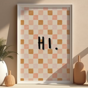 May include: A framed print with a checkered pattern in shades of pink and brown. The print says "HI." in black lettering.