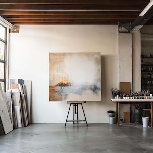 Peut inclure: Une grande peinture abstraite sur toile, avec des nuances de brun, de blanc et de bleu, est exposée sur un chevalet dans un studio. La peinture est de style contemporain, avec un accent sur la texture et la couleur.