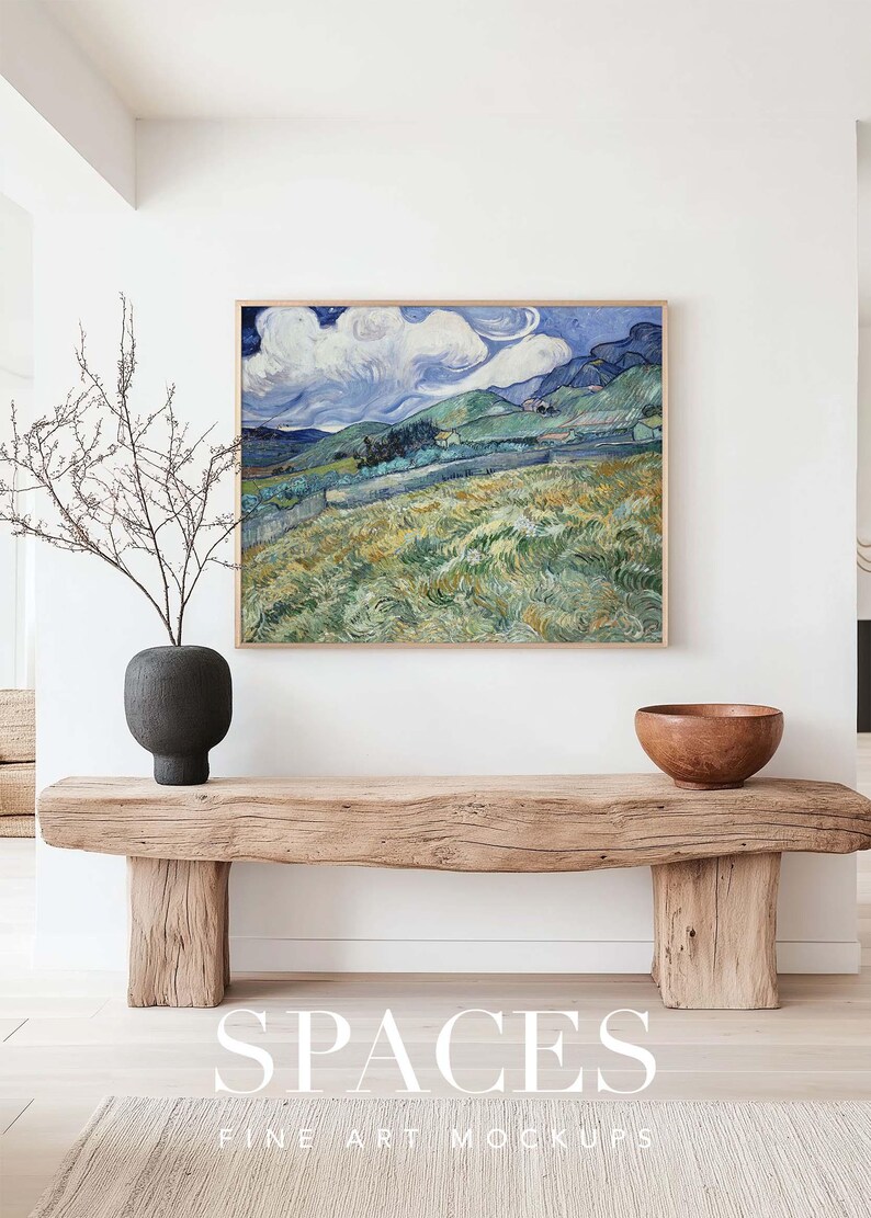 Puede incluir: Una pintura enmarcada de un paisaje con colinas onduladas, un cielo azul con nubes blancas y hierba verde. La pintura est&aacute; colgada en una pared blanca sobre un banco de madera. El banco est&aacute; hecho de madera toscamente labrada y tiene un acabado natural. El banco est&aacute; sentado en un suelo de madera clara. La pintura es una maqueta para una impresi&oacute;n de arte.