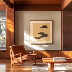 以下が含まれることがあります： 木製のパネル、茶色の革のアームチェア、低い木製のコーヒーテーブルを備えたミッドセンチュリーモダンなリビングルーム。 額入りの抽象芸術作品が壁に掛かっています。 ニュートラルなラグと自然光がシーンを完成させています。