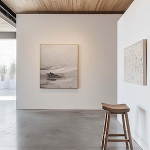 May include: A modern interior featuring a wooden stool with a curved seat and four legs. The room has white walls, a concrete floor, and a framed landscape artwork. The ceiling is made of wooden planks.