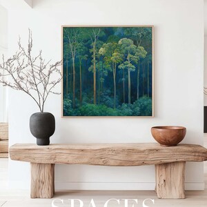Puede incluir: Una pintura enmarcada que representa una escena de bosque con &aacute;rboles altos y delgados en tonos verdes y azules. La pintura est&aacute; colgada en una pared blanca sobre un banco de madera con un cuenco en la parte superior.
