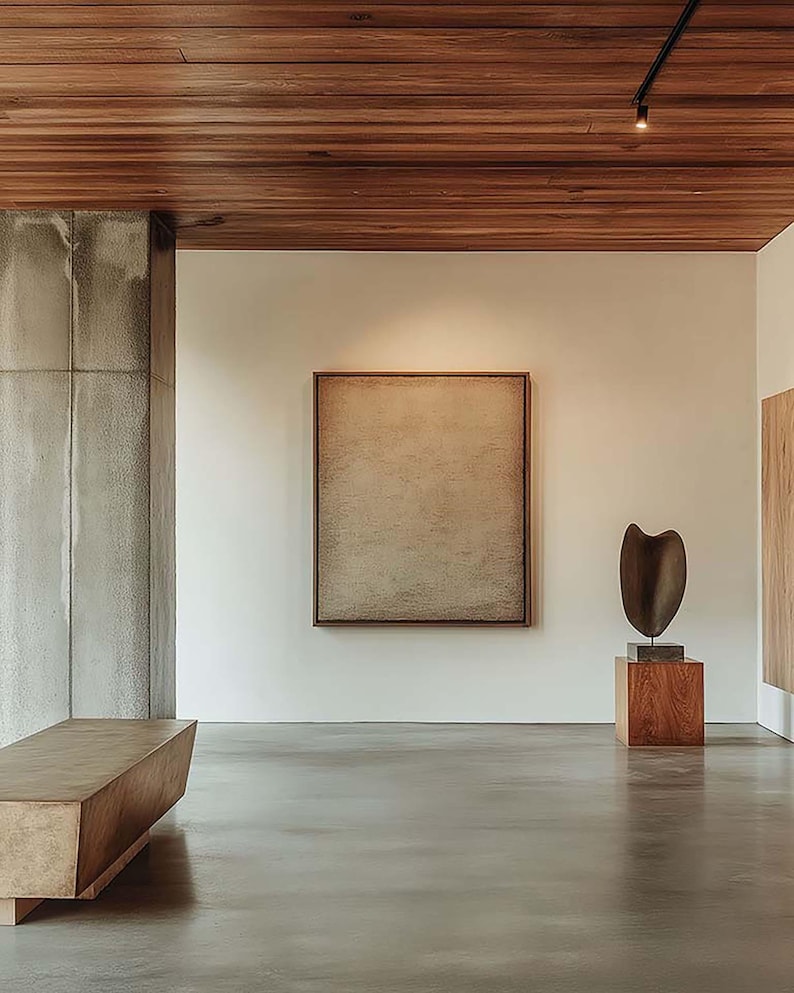 May include: An art gallery interior featuring a large framed abstract painting, a wooden bench, and a sculpture on a wooden pedestal. The ceiling is made of wood panels, and the floor is polished concrete.