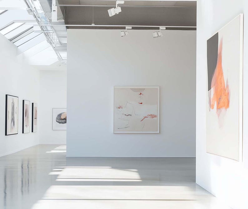 May include: A bright, modern art gallery with white walls and polished floors. Several framed abstract paintings are displayed, with a focus on neutral tones and soft colors. The space is well-lit with natural and artificial light.