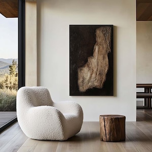Peut inclure: Un salon moderne avec un fauteuil rembourré arrondi de couleur crème et une petite table d'appoint en bois naturel. Une grande peinture abstraite aux tons marron et noir est accrochée au mur. De grandes fenêtres offrent une vue sur un paysage de montagne.