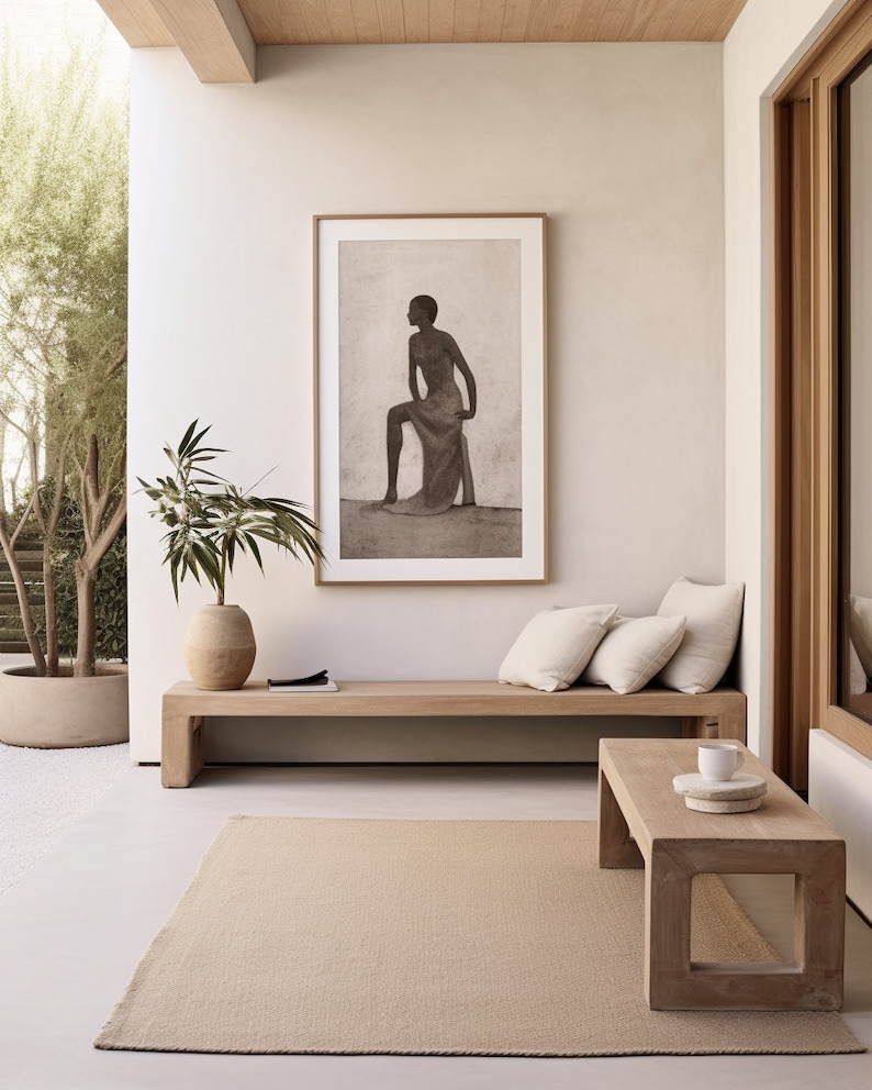 May include: A neutral-toned outdoor living space featuring a wooden bench with cream-colored pillows, a rectangular coffee table, and a beige rug. A framed black and white artwork hangs above the bench. A potted plant and a vase with greenery add natural elements.