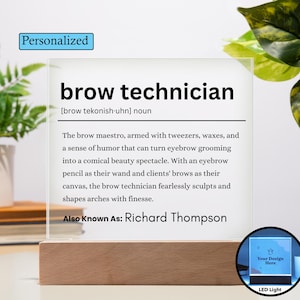 以下が含まれることがあります： 木製の台座が付いたパーソナライズされたLEDライト。透明なアクリルパネルには、「brow technician」というテキストと定義、そして「Richard Thompson」という名前が表示されています。デザインには、カスタムデザイン用の小さなエリアが含まれています。